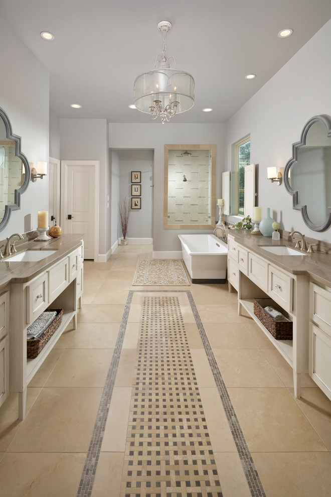 Inspiration for a large mediterranean master bathroom in Houston with an undermount sink, white cabinets, a freestanding tub, grey walls, porcelain floors, recessed-panel cabinets, beige floor and grey benchtops.