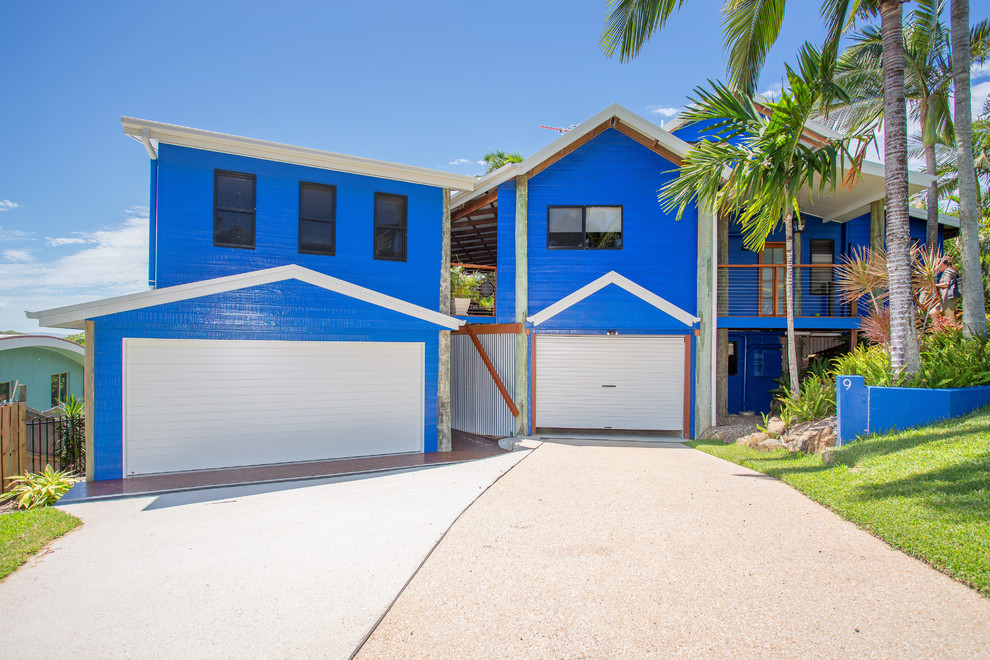 Photo of a large tropical two-storey blue house exterior in Other with wood siding, a gable roof and a metal roof.