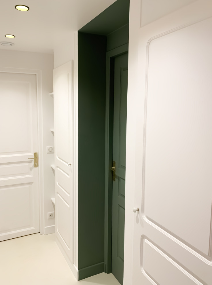 Photo of a small contemporary vestibule in Paris with white walls, concrete floors, a single front door, a white front door and white floor.