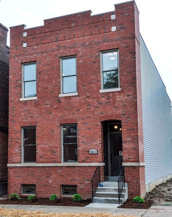 This is an example of a large two-storey brick exterior in St Louis with a flat roof.