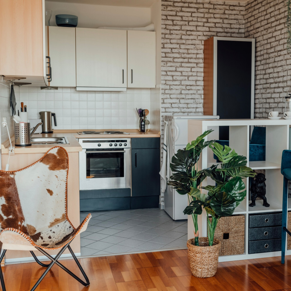 Small modern l-shaped open plan kitchen in Hamburg with a double-bowl sink, flat-panel cabinets, white cabinets, wood benchtops, white splashback, subway tile splashback, stainless steel appliances, cement tiles, no island and grey floor.