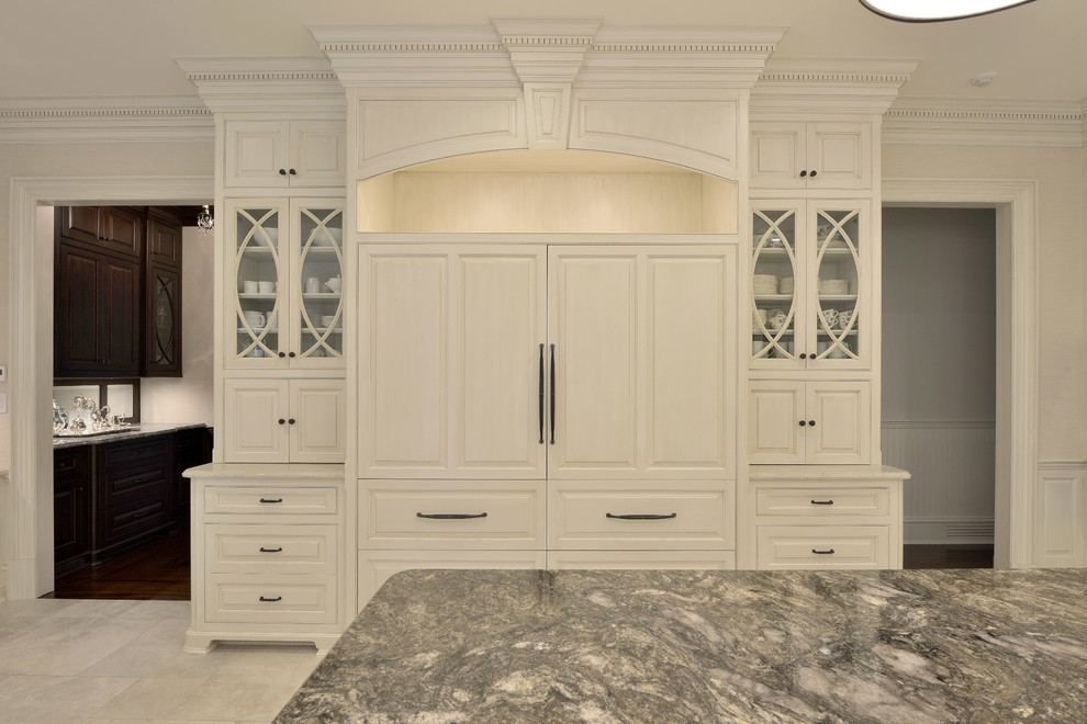 Photo of an expansive traditional u-shaped open plan kitchen in New York with an undermount sink, raised-panel cabinets, white cabinets, white splashback, stainless steel appliances, porcelain floors, with island, beige floor, multi-coloured benchtop, quartzite benchtops and subway tile splashback.