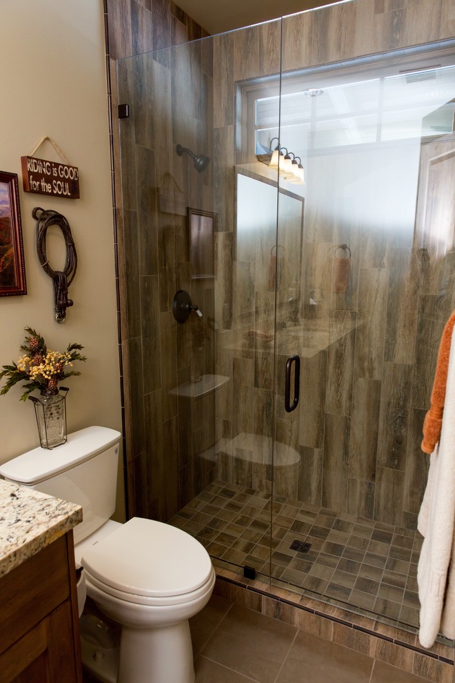 Inspiration for a mid-sized rustic 3/4 brown tile and porcelain tile alcove shower remodel in Phoenix with shaker cabinets, medium tone wood cabinets, a two-piece toilet, beige walls, an undermount sink, granite countertops, a hinged shower door and multicolored countertops