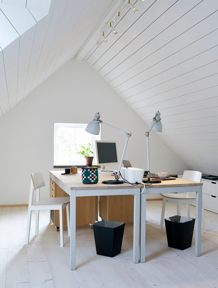 Photo of a mid-sized transitional study room in Stockholm with white walls, light hardwood floors, no fireplace and a freestanding desk.