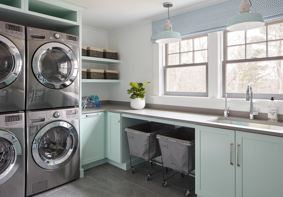 Inspiration for a beach style l-shaped dedicated laundry room in Boston with an undermount sink, shaker cabinets, green cabinets, white walls, grey floor and grey benchtop.