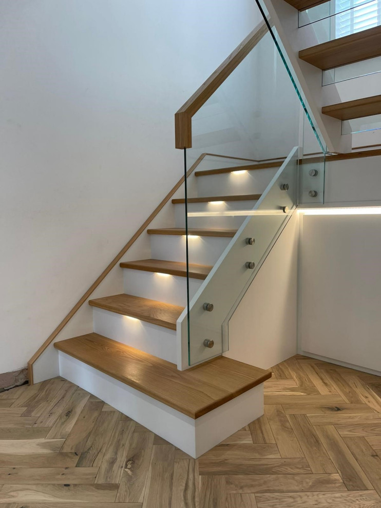 На фото: п-образная лестница среднего размера в стиле модернизм с деревянными ступенями и стеклянными перилами без подступенок
