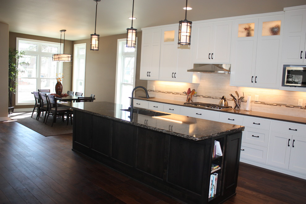 Example of a mid-sized transitional l-shaped dark wood floor open concept kitchen design with an undermount sink, recessed-panel cabinets, white cabinets, quartz countertops, beige backsplash, ceramic backsplash, stainless steel appliances and an island