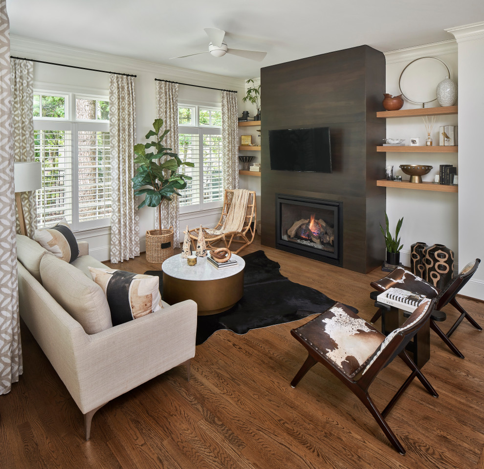 This is an example of a small contemporary formal open plan living room in Charlotte with white walls, medium hardwood flooring, a standard fireplace, a metal fireplace surround, a wall mounted tv and brown floors.