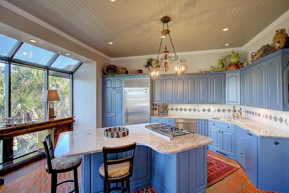 Design ideas for a mid-sized beach style l-shaped eat-in kitchen in Charleston with a double-bowl sink, blue cabinets, granite benchtops, multi-coloured splashback, ceramic splashback, stainless steel appliances, terra-cotta floors, with island, raised-panel cabinets and red floor.