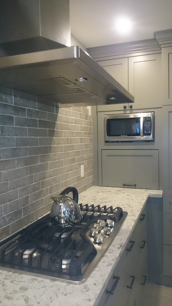 Example of a mid-sized transitional l-shaped porcelain tile eat-in kitchen design in Toronto with a double-bowl sink, shaker cabinets, gray cabinets, quartz countertops, multicolored backsplash, porcelain backsplash, stainless steel appliances and an island