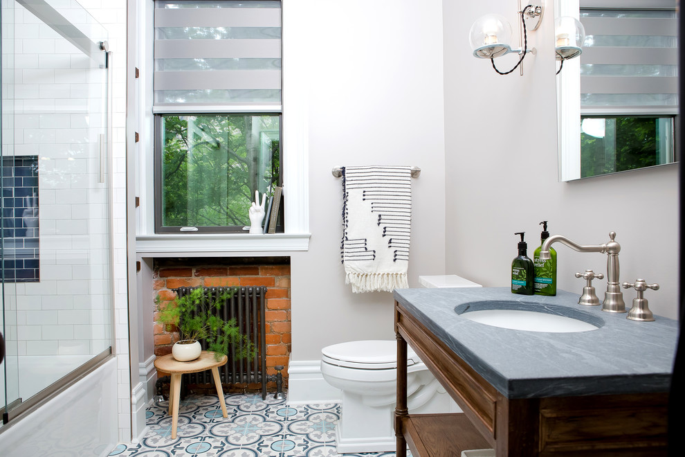 Inspiration for a small eclectic 3/4 bathroom in Other with furniture-like cabinets, medium wood cabinets, an alcove tub, an alcove shower, a one-piece toilet, blue tile, ceramic tile, grey walls, concrete floors, an undermount sink, marble benchtops, blue floor and a sliding shower screen.