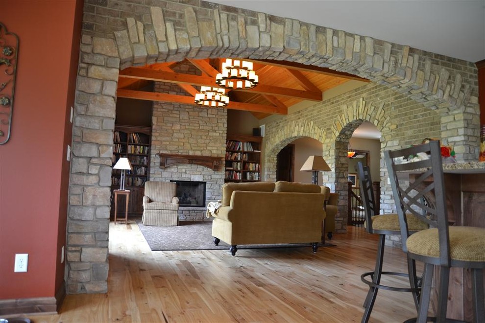 Large traditional open concept living room in Milwaukee with light hardwood floors, a standard fireplace, a stone fireplace surround, red walls and beige floor.