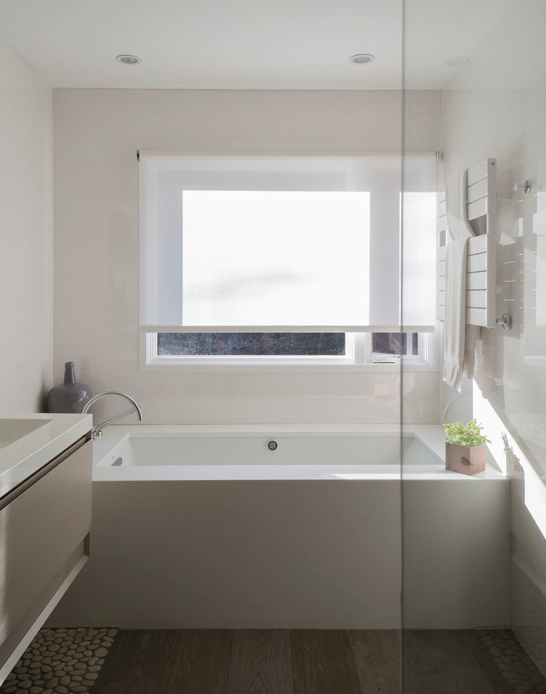 Design ideas for a small contemporary master bathroom in New York with flat-panel cabinets, beige cabinets, an undermount tub, beige walls, an integrated sink, a corner shower, multi-coloured tile, porcelain tile, porcelain floors and solid surface benchtops.