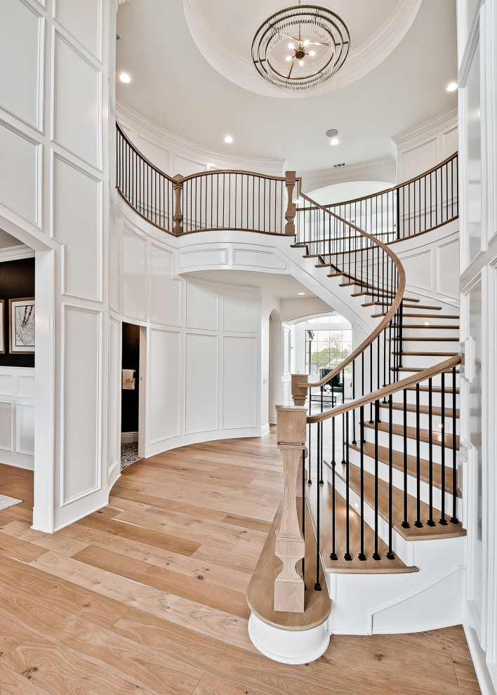 Diseño de escalera curva clásica renovada grande con escalones de madera, contrahuellas de madera, barandilla de madera y panelado