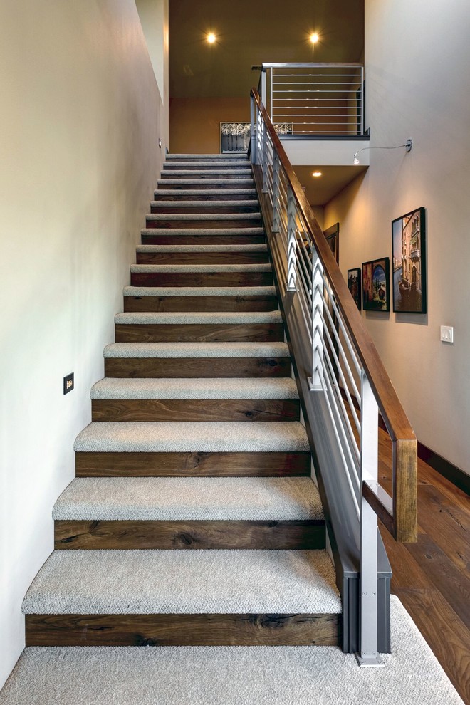 Photo of a large contemporary carpeted straight staircase in Seattle with wood risers and metal railing.