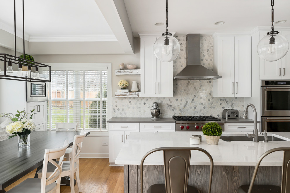Large transitional light wood floor open concept kitchen photo in Chicago with an undermount sink, shaker cabinets, white cabinets, quartz countertops, gray backsplash, marble backsplash, stainless steel appliances and an island