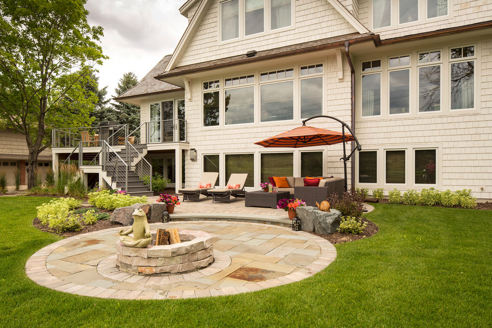 Mid-sized arts and crafts backyard patio in Minneapolis with with fireplace, natural stone pavers and an awning.