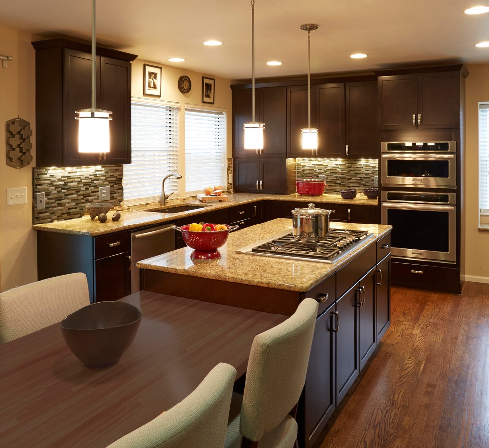 Large transitional l-shaped medium tone wood floor eat-in kitchen photo in Denver with an undermount sink, shaker cabinets, dark wood cabinets, laminate countertops, beige backsplash, glass sheet backsplash, stainless steel appliances and an island