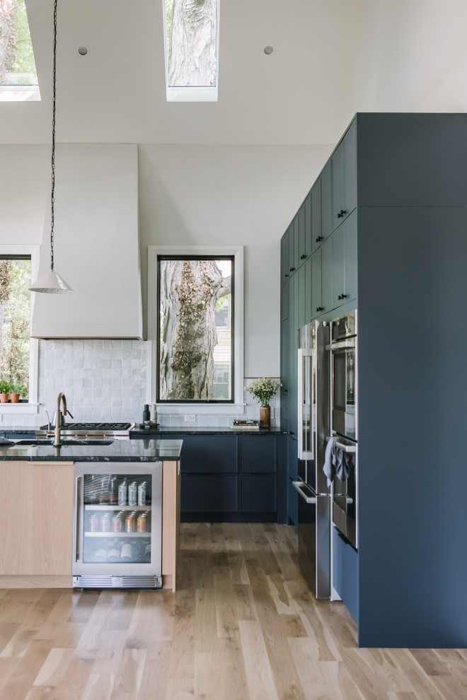 ローリーにある高級な中くらいな北欧スタイルのおしゃれなキッチン (シングルシンク、シェーカースタイル扉のキャビネット、青いキャビネット、御影石カウンター、白いキッチンパネル、セラミックタイルのキッチンパネル、シルバーの調理設備、淡色無垢フローリング、黄色い床、黒いキッチンカウンター、三角天井) の写真