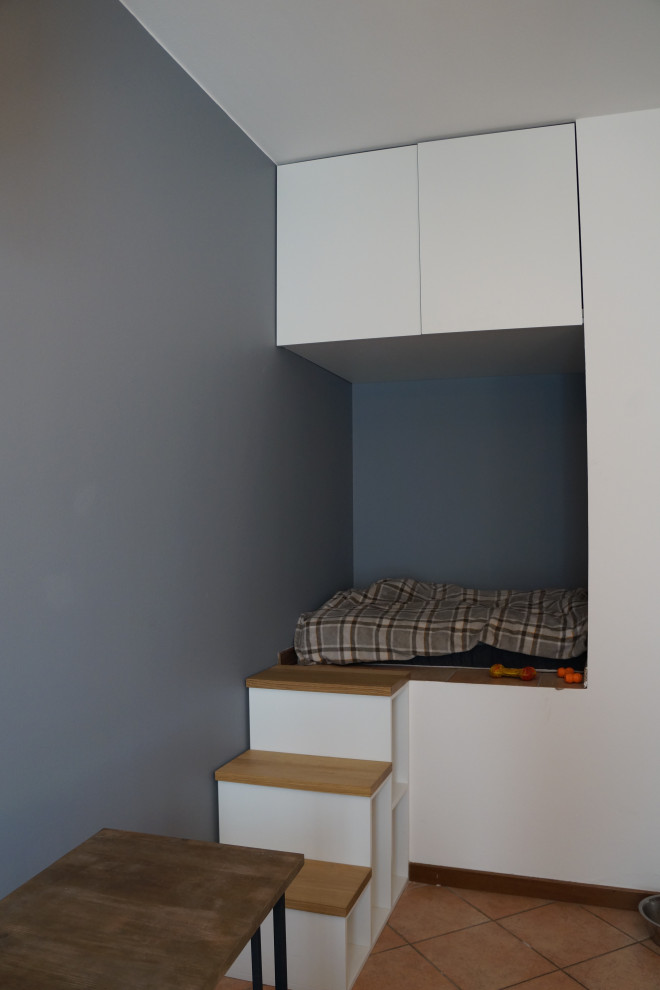Immagine di una piccola camera degli ospiti minimal con pareti grigie, pavimento in mattoni e pavimento rosso