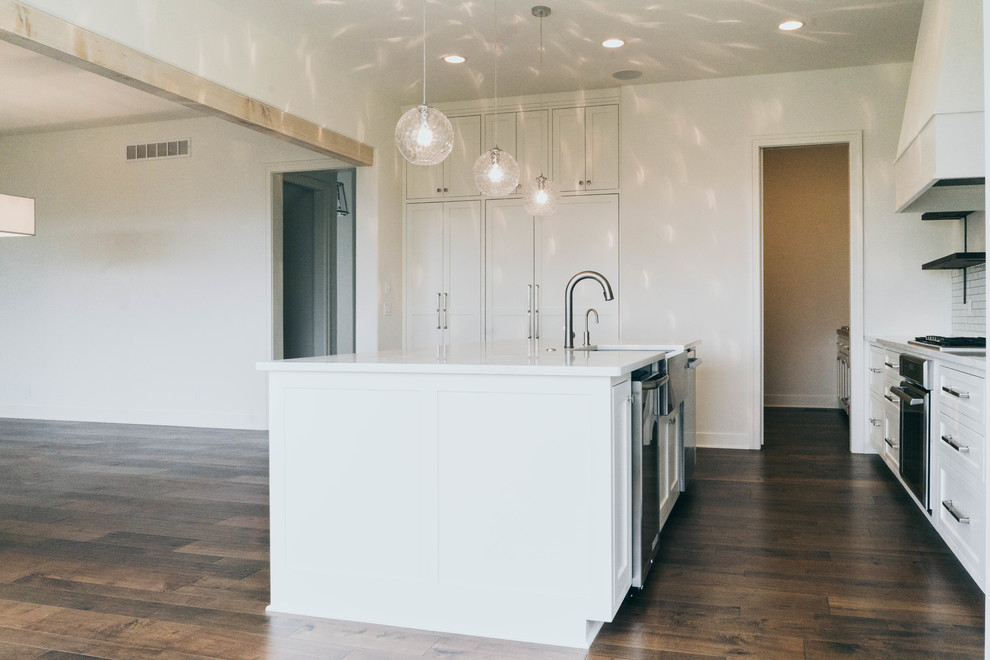 Example of a transitional dark wood floor enclosed kitchen design in Omaha with a farmhouse sink, shaker cabinets, white cabinets, quartz countertops, paneled appliances and an island