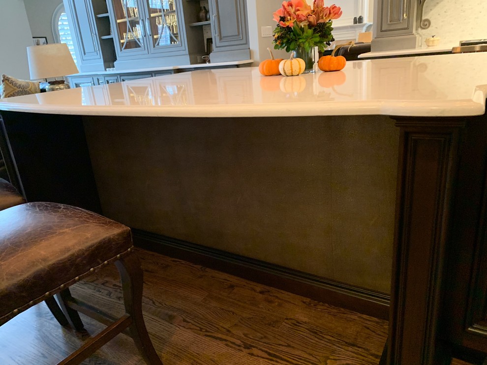 Large transitional single-wall medium tone wood floor and brown floor kitchen photo in Denver with a single-bowl sink, beaded inset cabinets, gray cabinets, quartz countertops, mosaic tile backsplash, paneled appliances, an island and beige countertops