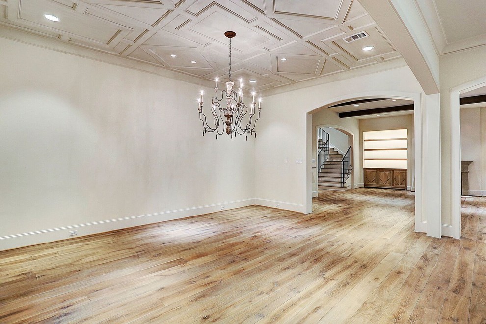 This is an example of a transitional living room in Houston with white walls and light hardwood floors.