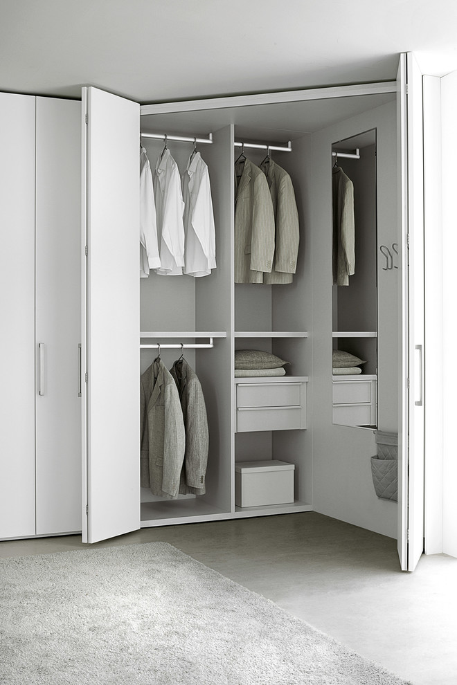 Inspiration for a large modern gender-neutral built-in wardrobe in New York with flat-panel cabinets, white cabinets and concrete floors.