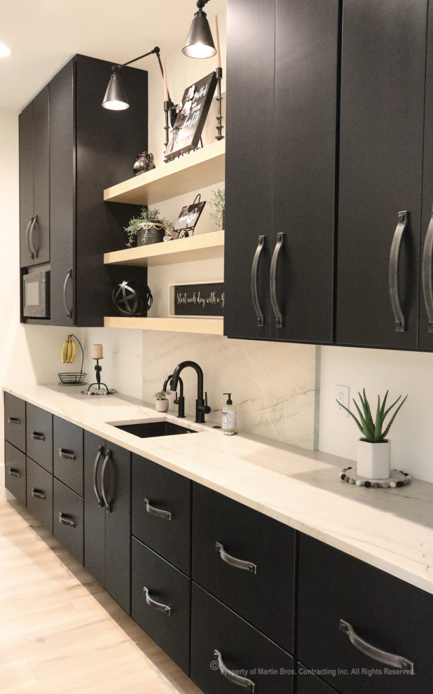 Inspiration for a large urban galley kitchen pantry in Other with a submerged sink, shaker cabinets, black cabinets, quartz worktops, white splashback, stone slab splashback, black appliances, light hardwood flooring, an island, white worktops and a timber clad ceiling.