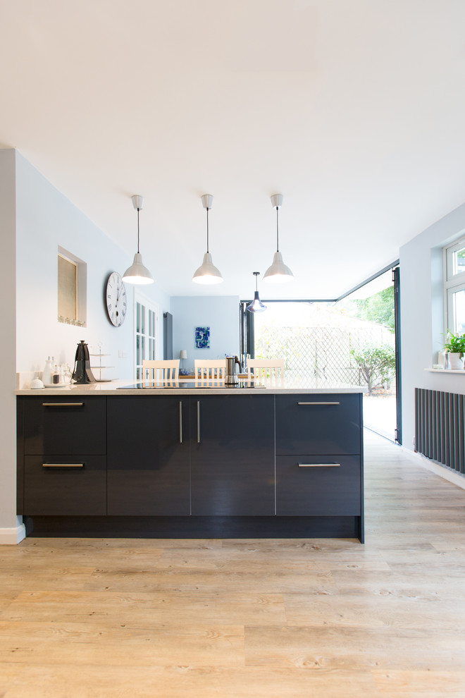 This is an example of a mid-sized contemporary u-shaped open plan kitchen in Surrey with flat-panel cabinets, grey cabinets, quartzite benchtops and with island.