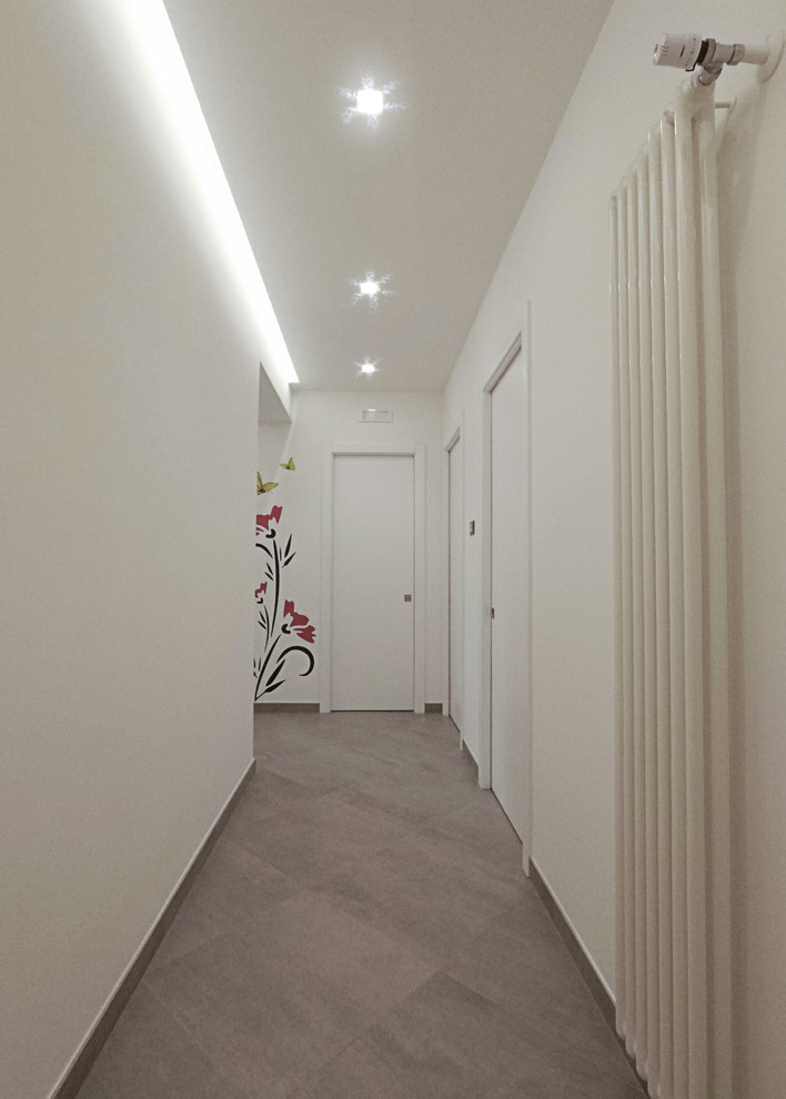 Ispirazione per un ingresso o corridoio minimal di medie dimensioni con pareti bianche, pavimento in gres porcellanato e pavimento grigio