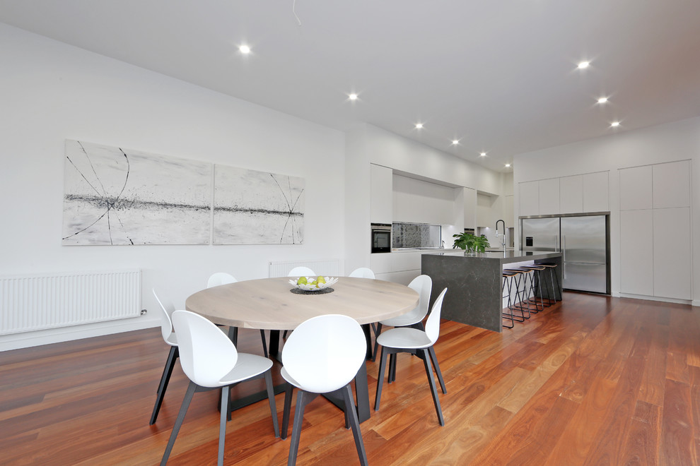 Design ideas for a contemporary u-shaped eat-in kitchen in Melbourne with flat-panel cabinets, white cabinets, stainless steel appliances, medium hardwood floors and with island.
