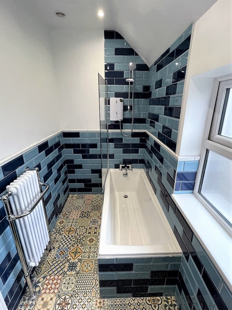 Пример оригинального дизайна: детская ванная комната среднего размера в классическом стиле с фасадами в стиле шейкер, синими фасадами, отдельно стоящей ванной, душем над ванной, унитазом-моноблоком, синей плиткой, керамогранитной плиткой, белыми стенами, полом из керамогранита, врезной раковиной, столешницей из кварцита, разноцветным полом, белой столешницей, тумбой под одну раковину и напольной тумбой