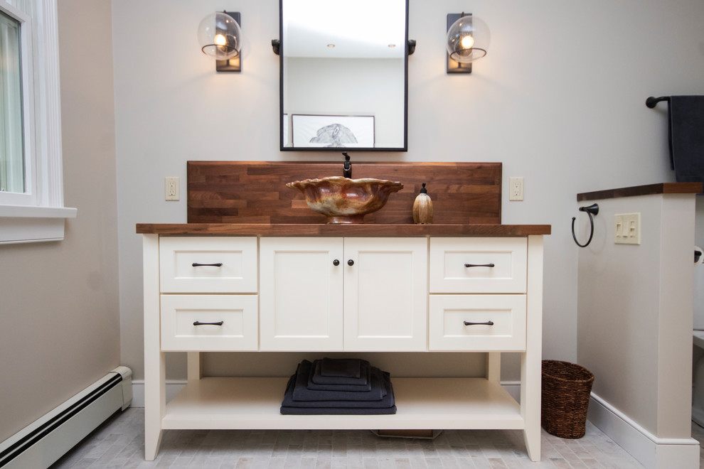 Photo of an expansive country master bathroom in Providence with furniture-like cabinets, white cabinets, a drop-in tub, a corner shower, a two-piece toilet, beige tile, porcelain tile, beige walls, porcelain floors, a vessel sink, wood benchtops, white floor and a hinged shower door.
