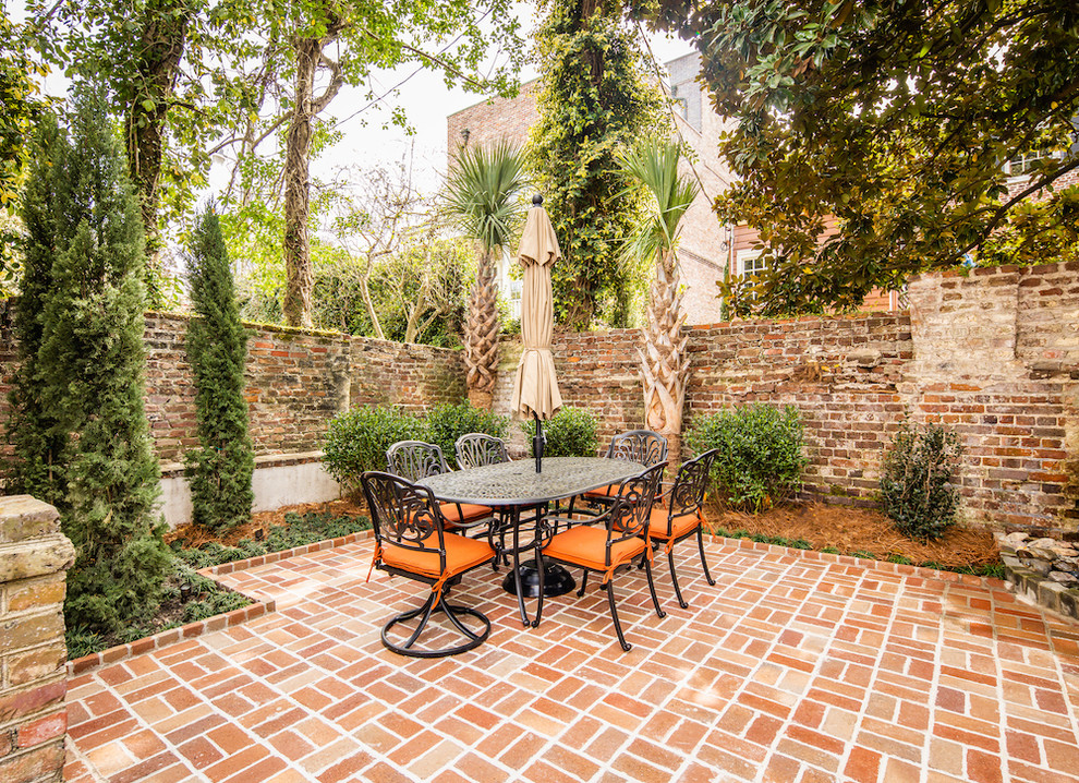This is an example of a traditional backyard patio in Charleston with brick pavers and no cover.