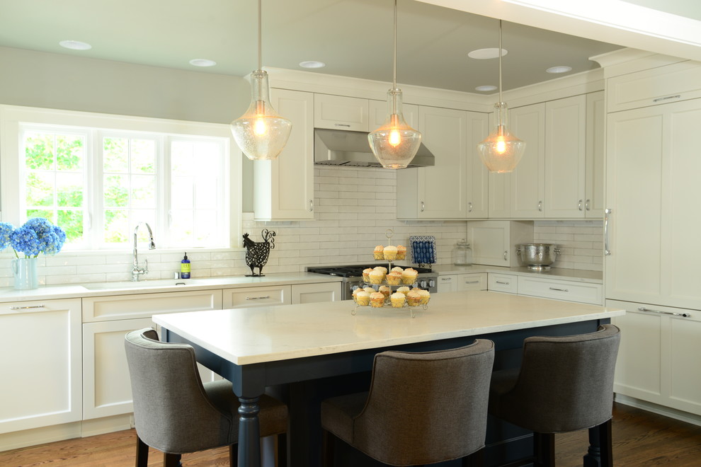 Inspiration for a large transitional l-shaped medium tone wood floor eat-in kitchen remodel in Seattle with an undermount sink, shaker cabinets, quartz countertops, white backsplash, subway tile backsplash, paneled appliances and an island