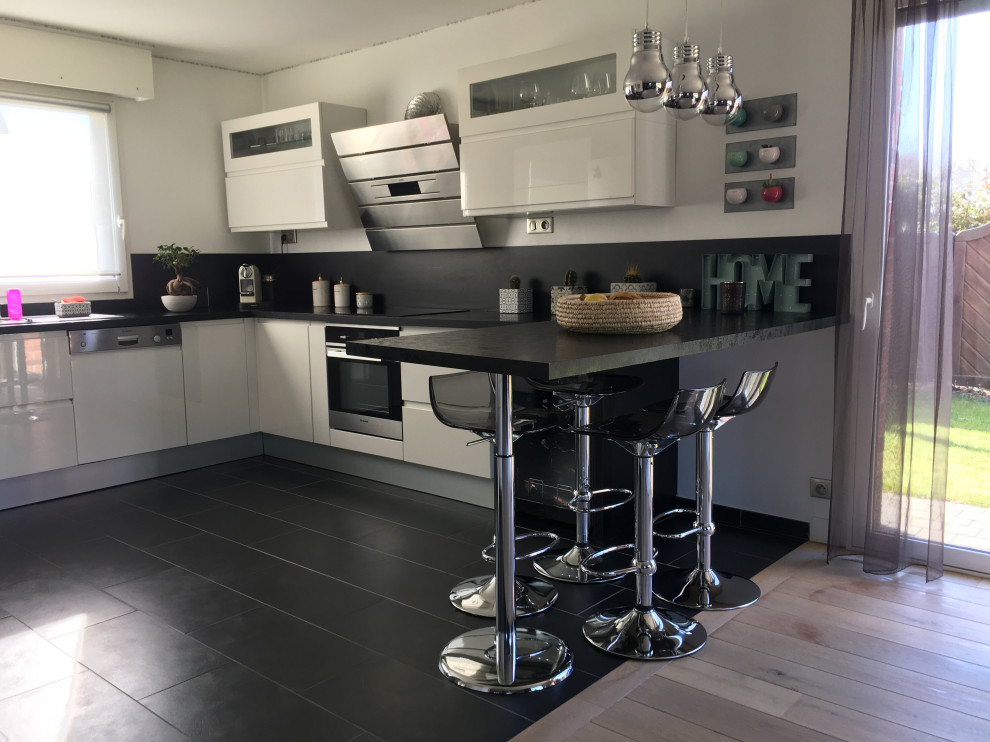 Inspiration för stora moderna svart kök, med en undermonterad diskho, luckor med upphöjd panel, skåp i rostfritt stål, bänkskiva i kvartsit, svart stänkskydd, integrerade vitvaror och svart golv