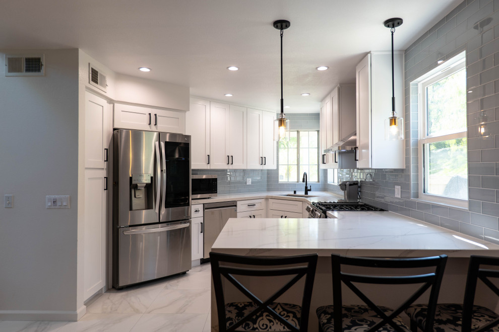 Medium sized modern u-shaped enclosed kitchen in Los Angeles with a built-in sink, raised-panel cabinets, white cabinets, granite worktops, blue splashback, metro tiled splashback, stainless steel appliances, marble flooring, no island, white floors and white worktops.
