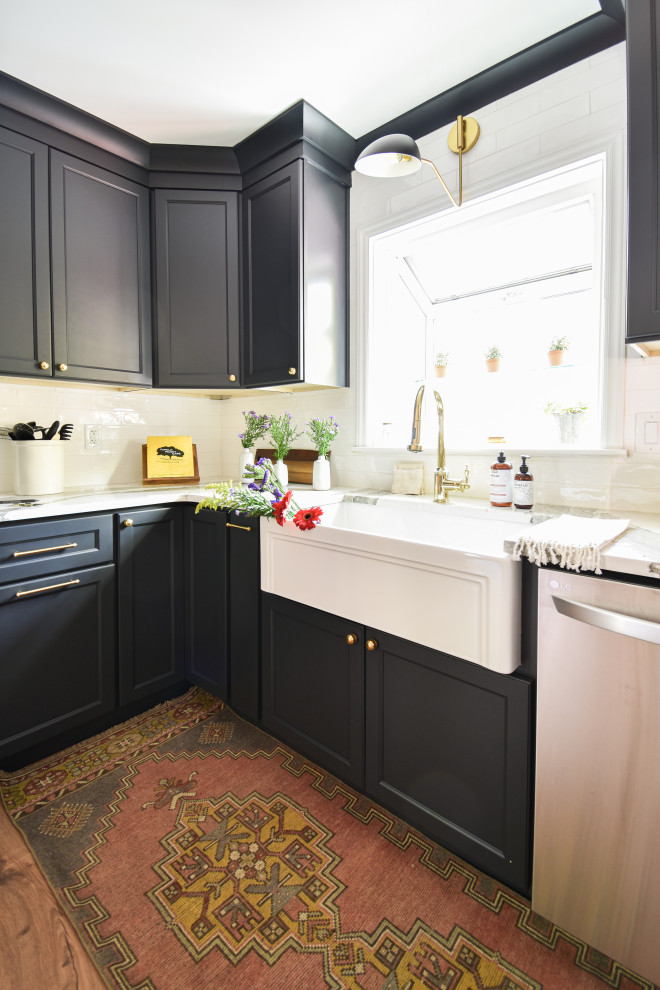 Example of a mid-sized transitional u-shaped laminate floor open concept kitchen design with a farmhouse sink, black cabinets, quartzite countertops, white backsplash and a peninsula