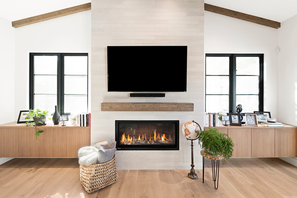 Design ideas for a mid-sized country enclosed family room in San Francisco with white walls, light hardwood floors, a standard fireplace, a tile fireplace surround, a wall-mounted tv and brown floor.