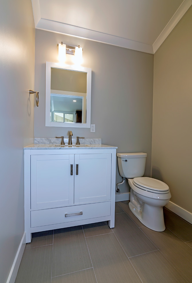 Photo of a small contemporary powder room in San Francisco with an undermount sink, shaker cabinets, white cabinets, granite benchtops, a two-piece toilet, gray tile, beige walls and porcelain floors.