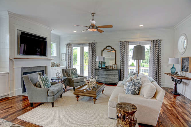 Photo of a mid-sized beach style open concept family room in Wilmington with white walls, medium hardwood floors, a standard fireplace, a wall-mounted tv, a tile fireplace surround and brown floor.