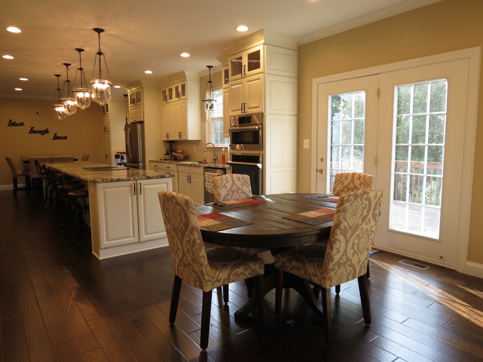 Inspiration for a large transitional galley dark wood floor and brown floor kitchen remodel with a double-bowl sink, raised-panel cabinets, white cabinets, granite countertops, white backsplash, porcelain backsplash, stainless steel appliances and an island