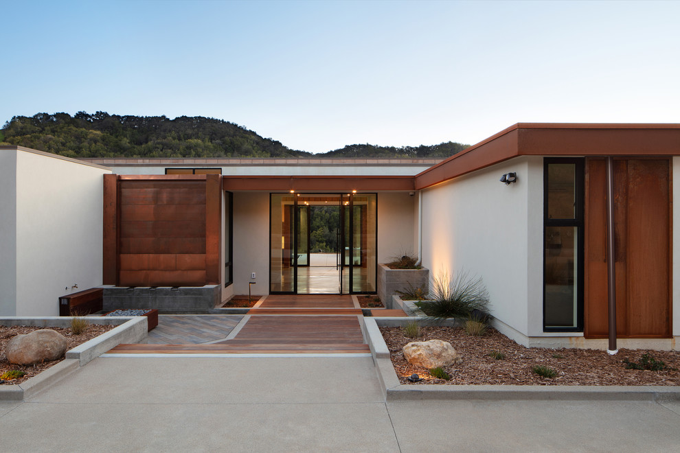 This is an example of a large contemporary front door in San Luis Obispo with white walls, concrete floors, a pivot front door, a glass front door and brown floor.