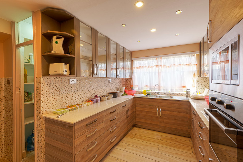 This is an example of a small modern u-shaped separate kitchen in Other with a double-bowl sink, glass-front cabinets, medium wood cabinets, granite benchtops, multi-coloured splashback, mosaic tile splashback, stainless steel appliances, ceramic floors, no island, brown floor and white benchtop.