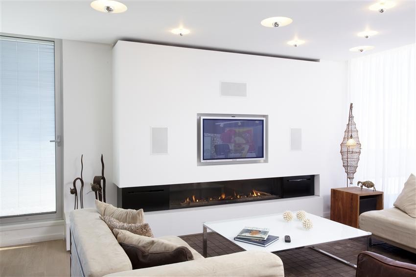 This is an example of a modern living room in Denver with white walls, light hardwood floors, a ribbon fireplace and a plaster fireplace surround.