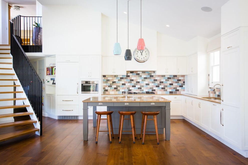 Inspiration for a large modern l-shaped open plan kitchen in Sydney with an undermount sink, shaker cabinets, white cabinets, multi-coloured splashback, stainless steel appliances, medium hardwood floors, with island, limestone benchtops, ceramic splashback and brown floor.