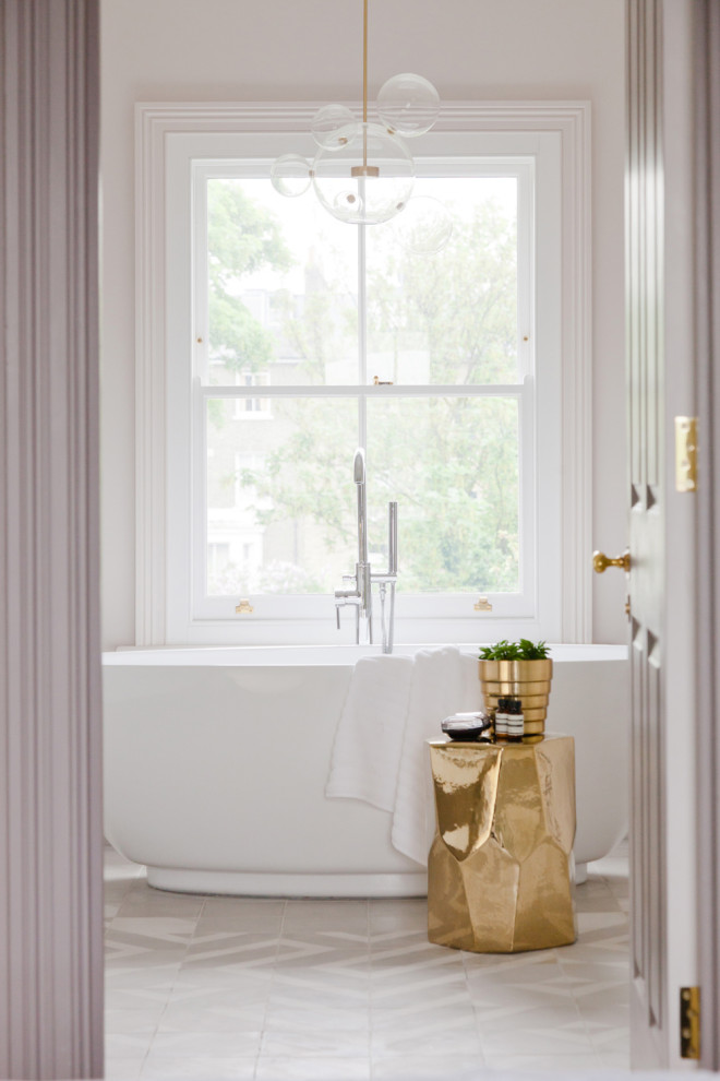 This is an example of a transitional bathroom in London with a freestanding tub, white walls and grey floor.