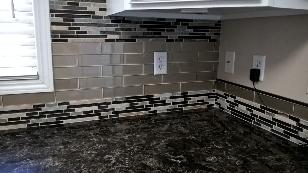 Example of a transitional kitchen design with a double-bowl sink, raised-panel cabinets, white cabinets, granite countertops, multicolored backsplash, glass tile backsplash and stainless steel appliances