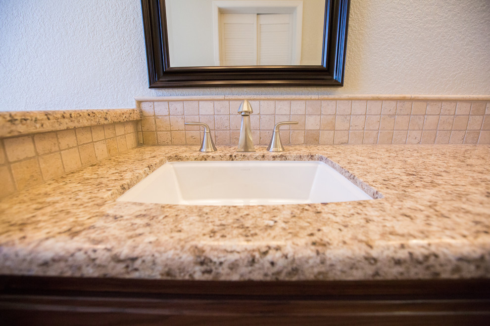 Photo of a large traditional bathroom in Sacramento with dark wood cabinets, an undermount tub, beige tile, porcelain floors, an undermount sink, granite benchtops and brown floor.